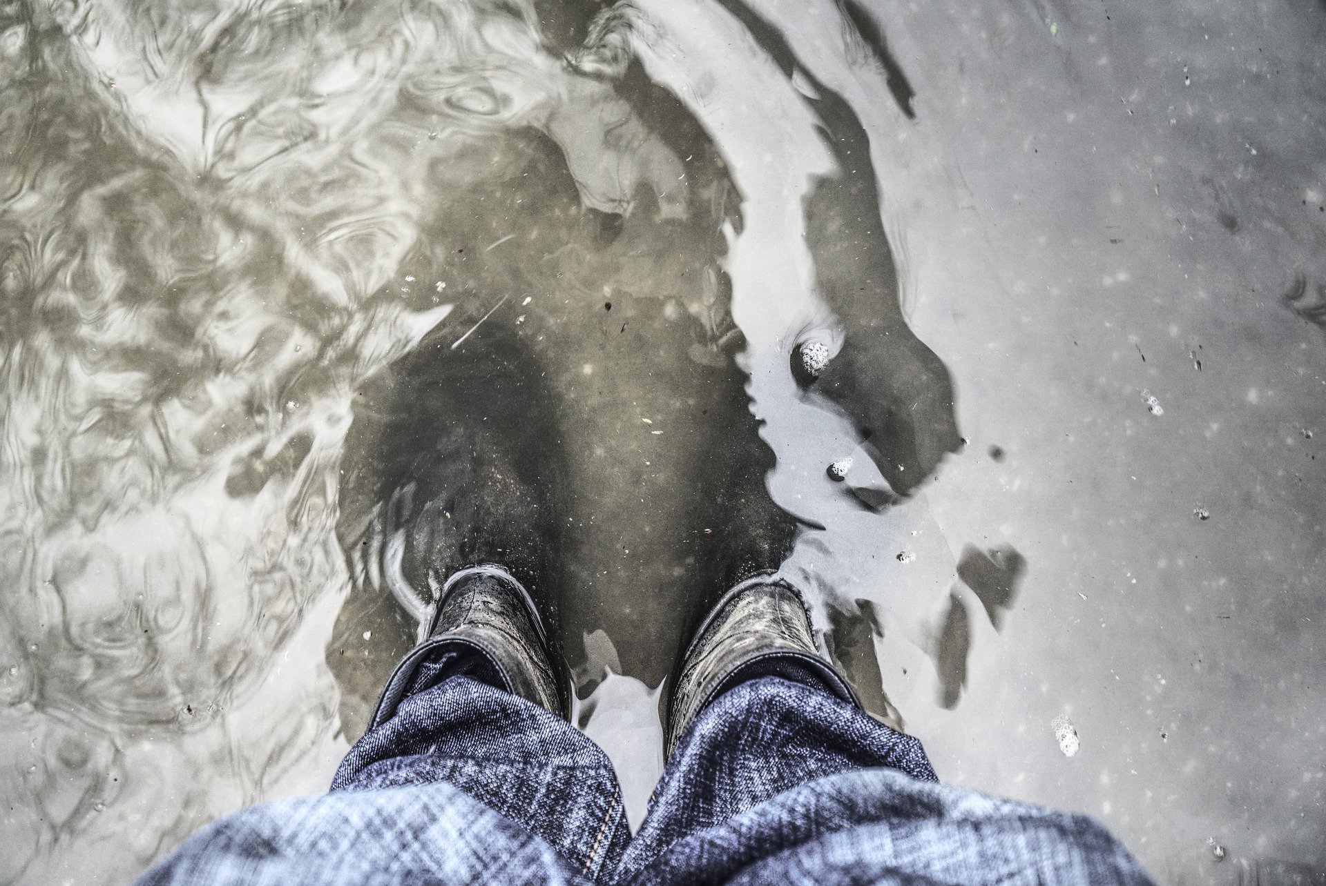 Beispielbild Havarie: Füße mit Gummistiefeln im Wasser darunter Betonboden, CC0-Foto Markus Distelrath