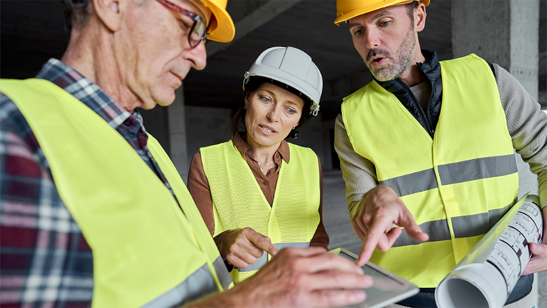 3 Menschen auf einer Baustelle in Schutzkleidung blicken auf ein Tablet und diskutieren (Foto: CC0 Gpoint Studio)